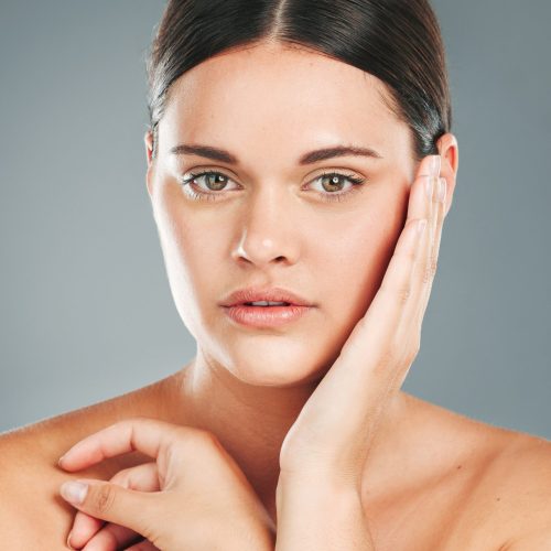 Beauty, portrait and woman hands touching face in studio for wellness, luxury facial and cosmetics. Young female model, aesthetic skincare and dermatology from healthy shine, glow and salon results.