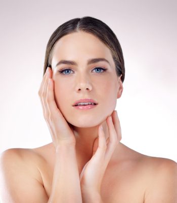 Beauty, skincare and portrait of woman with makeup, glow or wellness isolated on studio background. Cosmetic, hands or confident model touch face in spa for dermatology, health or shine for aesthetic.