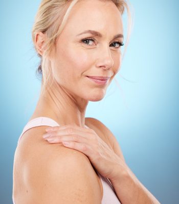 Beauty, woman and portrait in studio for skincare, dermatology and wellness cosmetics on blue background. Happy mature female model, facial and smile for aesthetic glow, laser transformation and face.