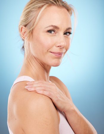Beauty, woman and portrait in studio for skincare, dermatology and wellness cosmetics on blue background. Happy mature female model, facial and smile for aesthetic glow, laser transformation and face.