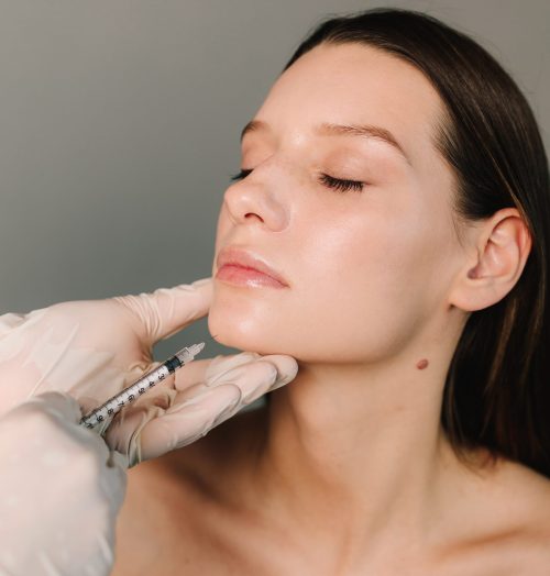 Cosmetologist making filler injection in female chin. Improving the shape of the chin by high quality doctor. Beauty treatment of face correction