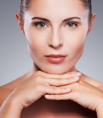 Fresh and beautiful. Portrait of shirtless mature woman looking at her shoulder while standing against grey background