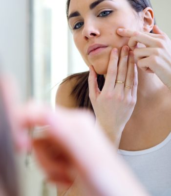 Portrait of woman caring of her beautiful skin on the face standing near mirror in the bathroom.